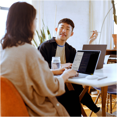 Two people in conversation while learning to code with Codecademy on their laptops